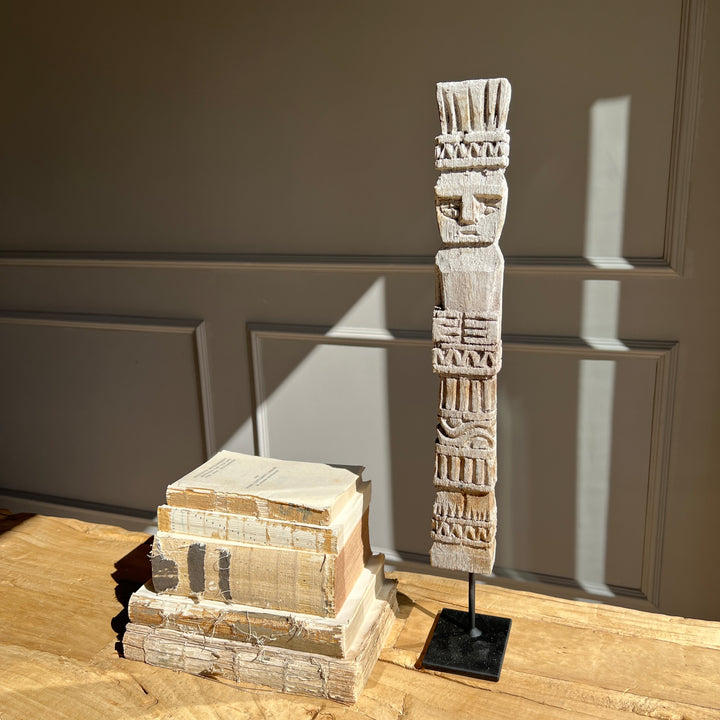 Vintage Balinese wooden statue on stand with books in the background