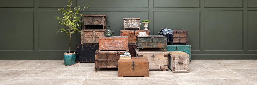 a rustic monogrammed antique champagne crate displayed on a stripped pine floor and filled with sumptuous sheepskin throws