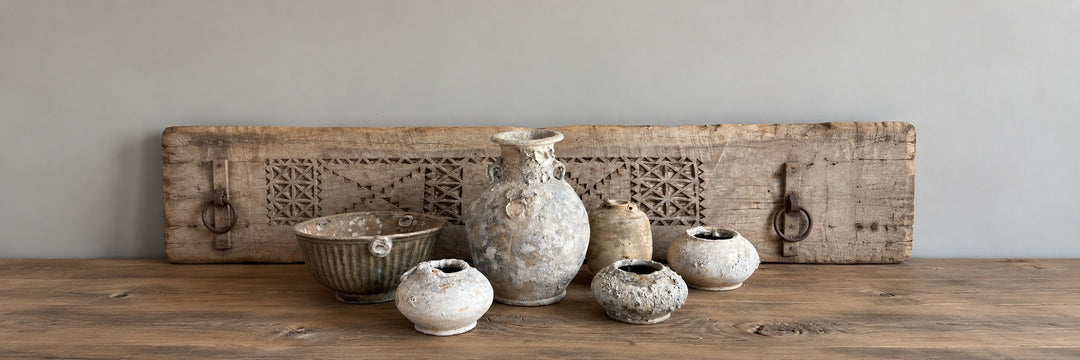 Collection of Decorative Antiques, including an Antique green French Carboy, rustic vintage wood bowl, vintage book bundle and antique coal displayed on reclaimed wood sideboard