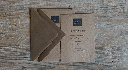 A Home Barn gift card displayed with it's envelope on a Home Barn rustic wood antique  table