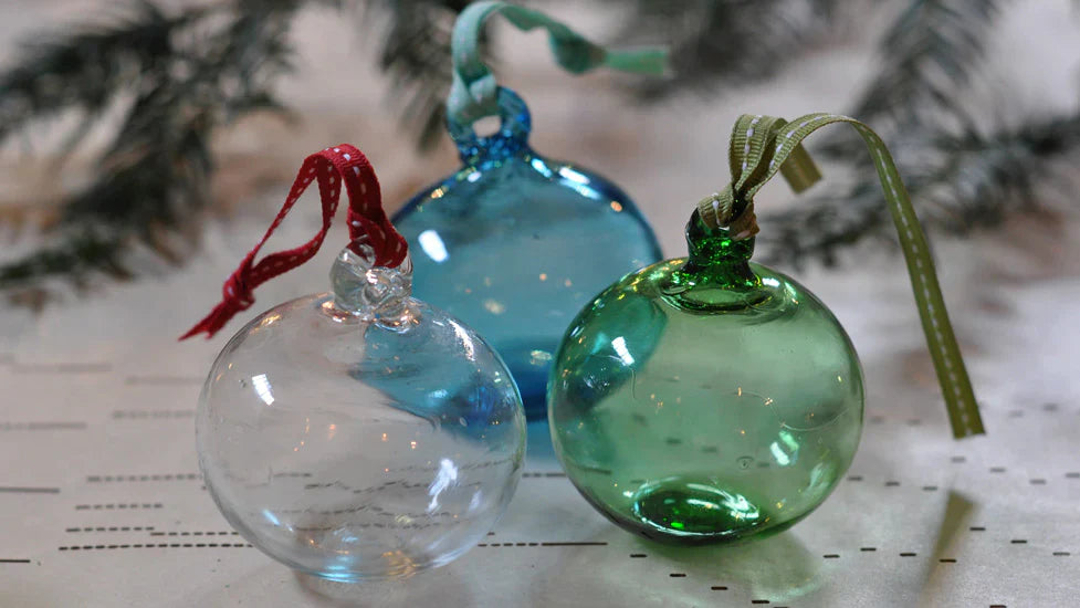 Three clear glass handblown glass baubles displayed as a table decoration on a handcrafted salvaged dining table