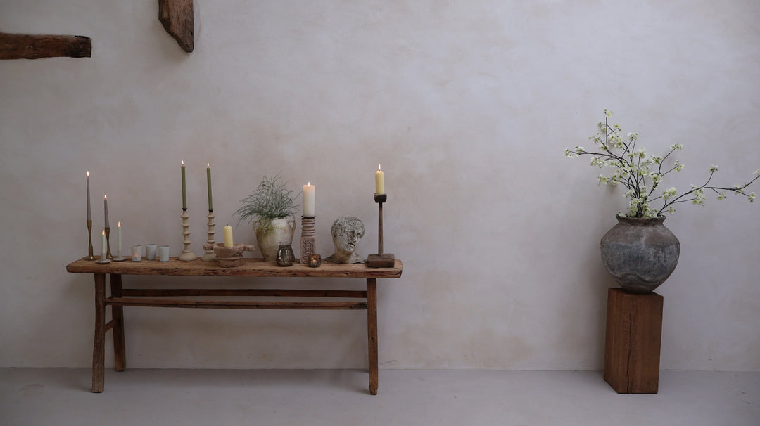A collection of candles and candle holders on top of a Home barn antique console table