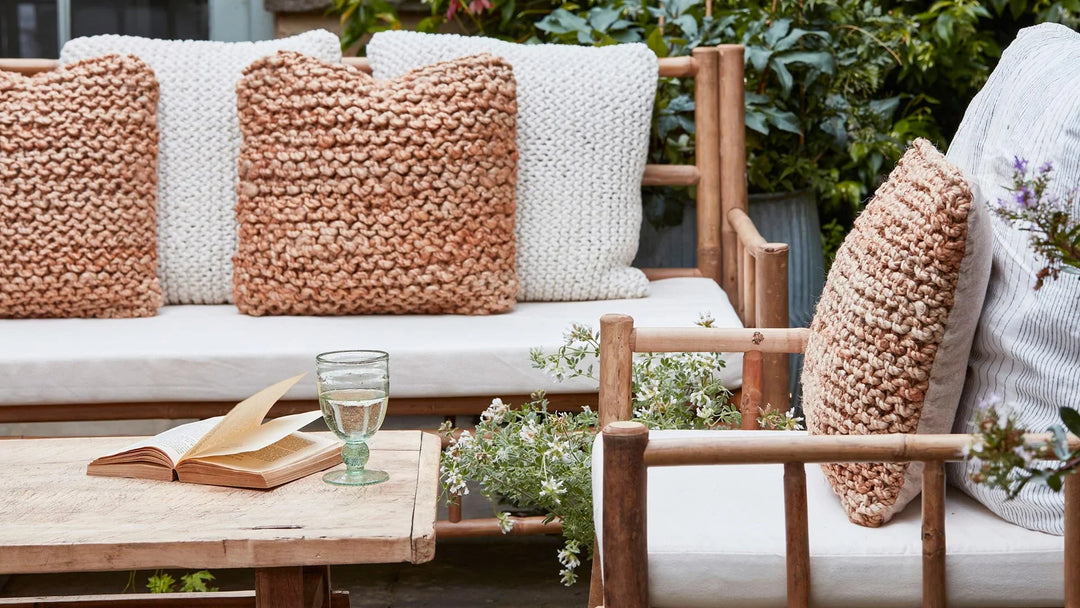 Outdoor Bamboo garden sofa and armchair set in a small patio garden and surrounded by lush greenery and wildflower planters around a rustic Home Barn antique coffee table