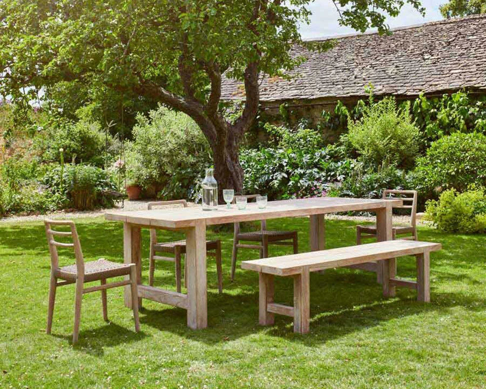 A large reclaimed wood dining table under an apply tree in an English country garden