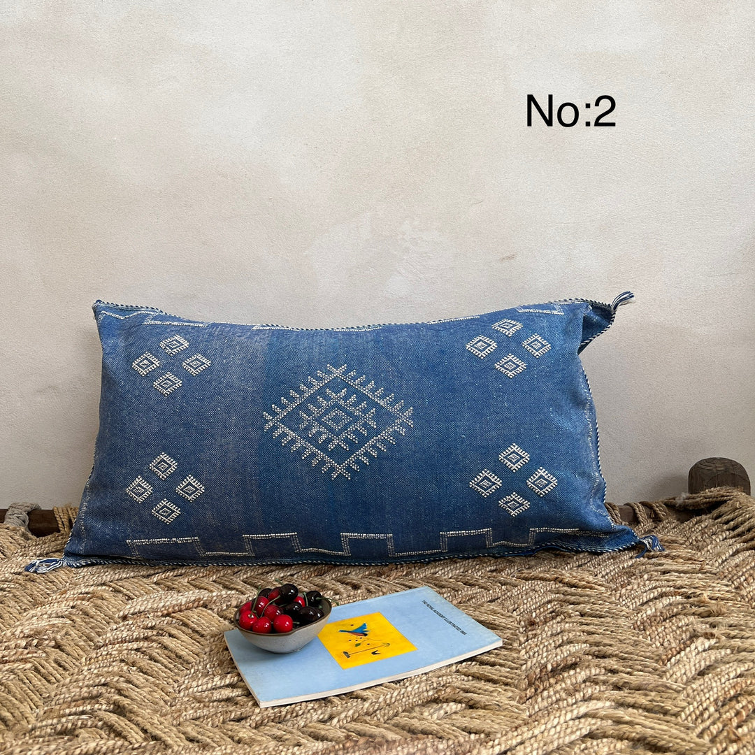 Blue embroidered pillow on a textured surface with a neutral background