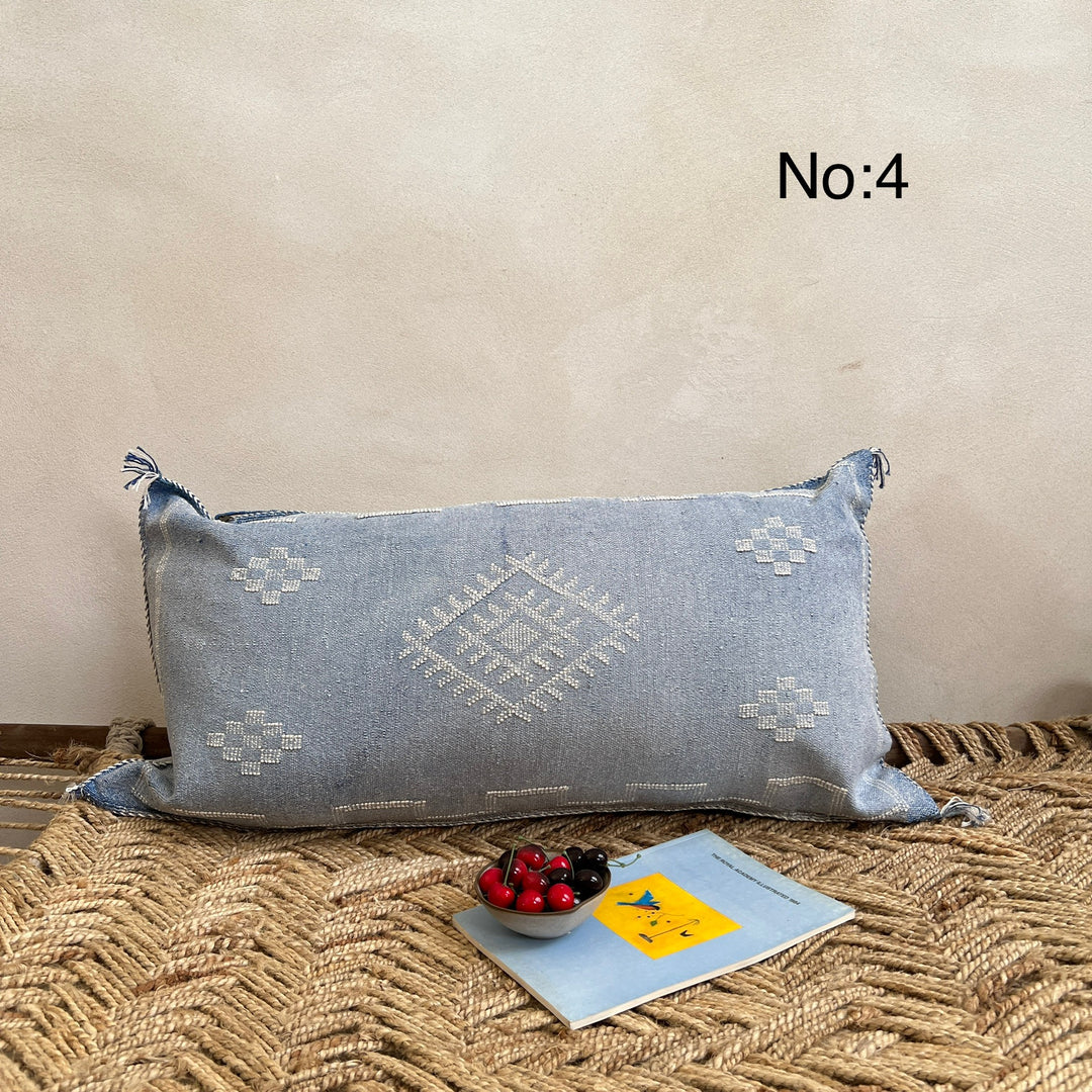 Decorative blue pillow with geometric patterns on a textured surface.