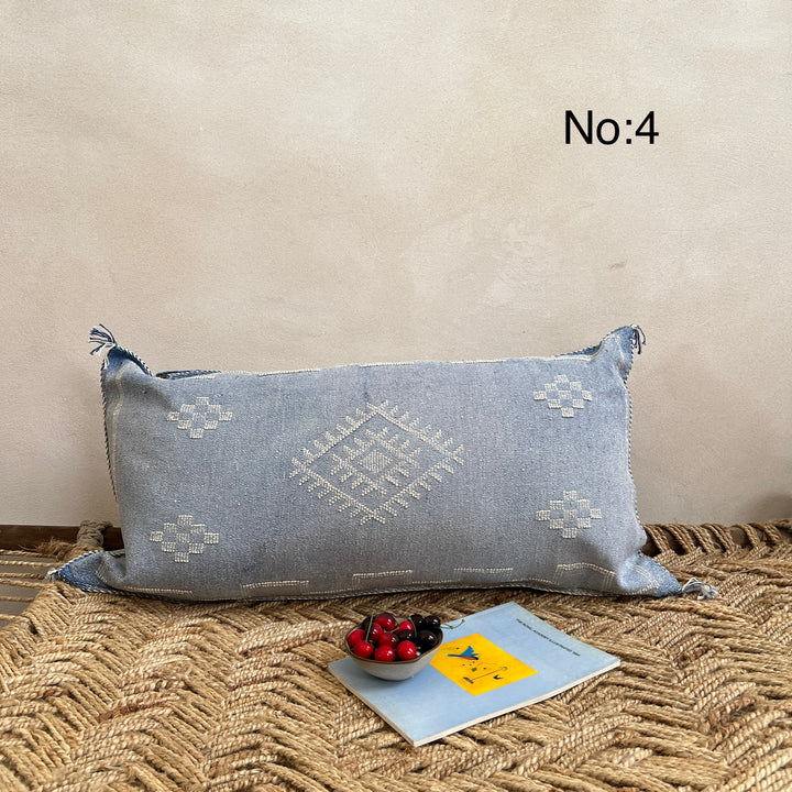 Decorative blue pillow with geometric patterns on a textured surface.
