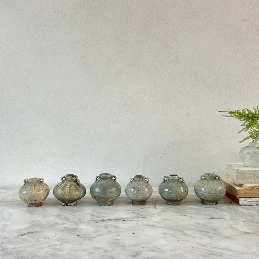 Row of ceramic vases on a marble surface with a neutral background