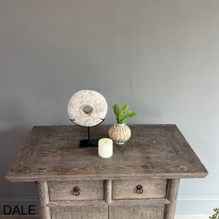 Wooden sideboard with decorative items on a plain wall background