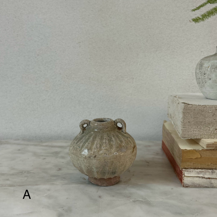 Small ceramic vase on a marble surface with a neutral background