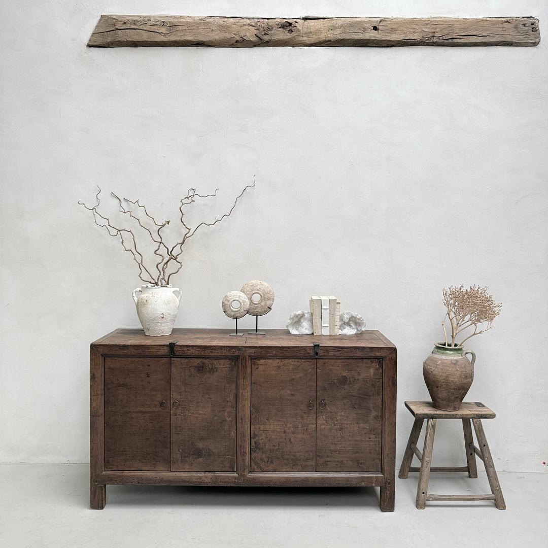 Wooden sideboard with decorative items against a white wall