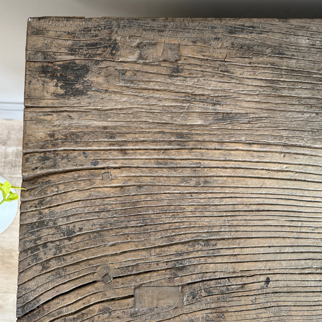 A close-up of a rustic, weathered wooden board with prominent horizontal grain, knots, and dark charred areas, showing natural brown and gray tones.