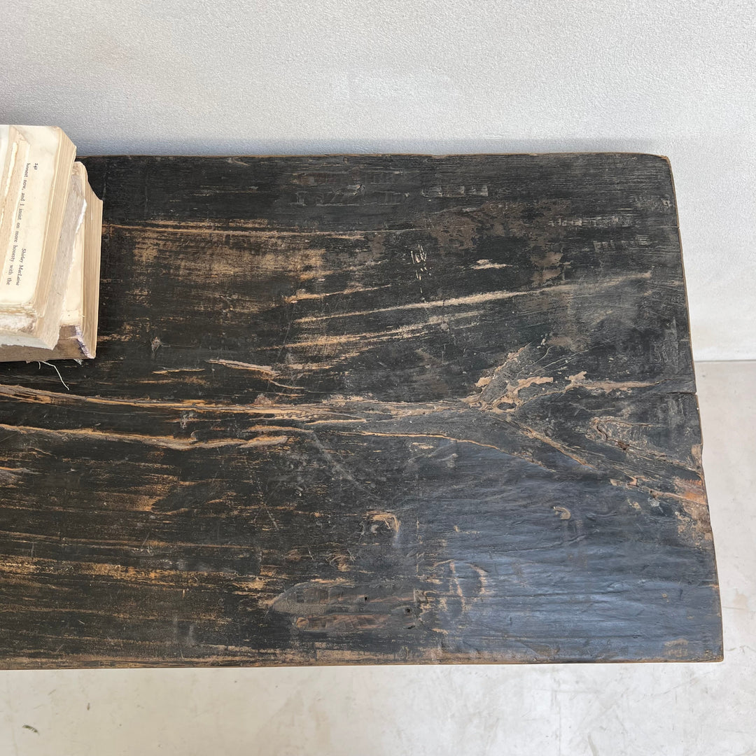 Dark wooden surface with visible wear and tear, next to an open book.