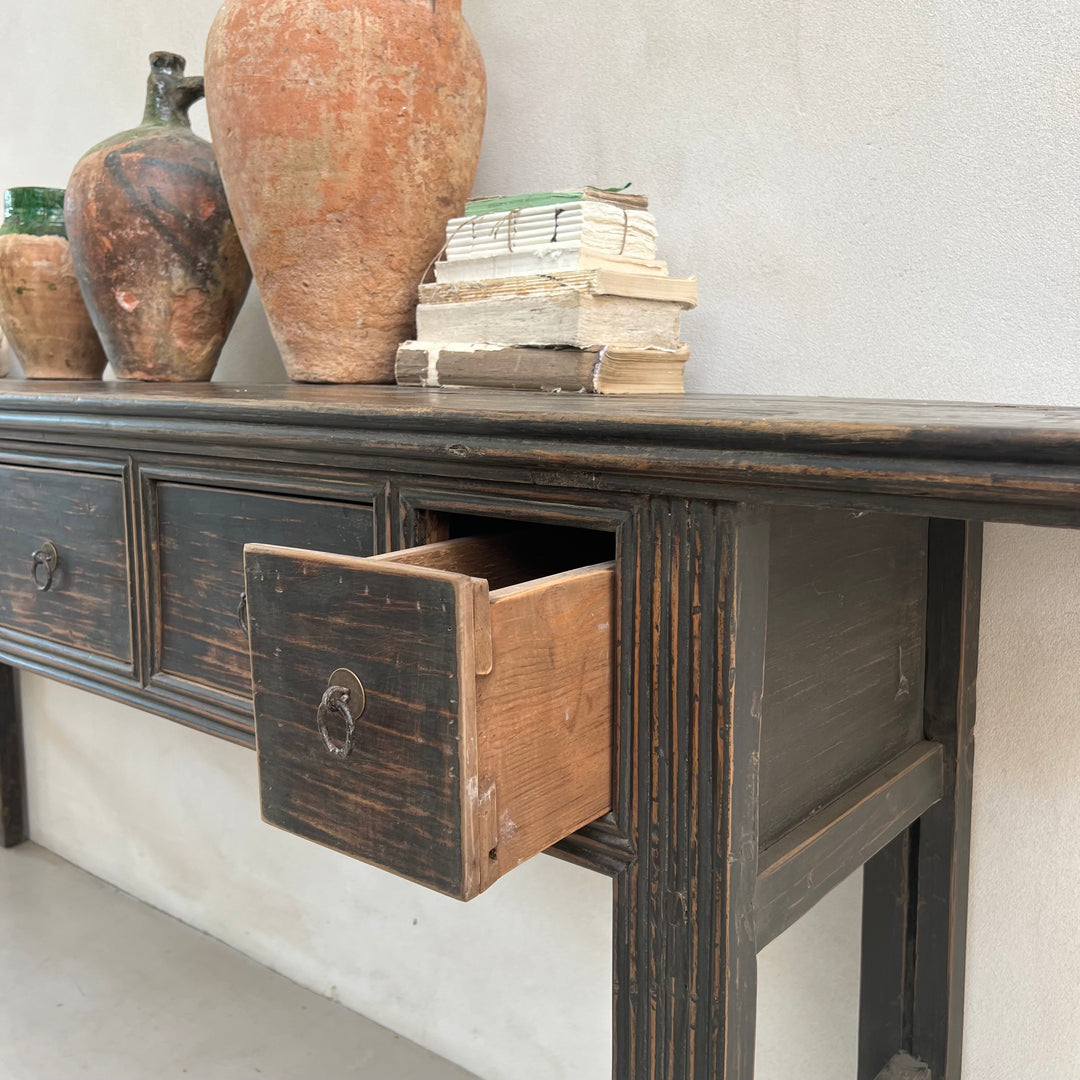 Wooden console table with open drawer, decorative vases, and books on a light gray background