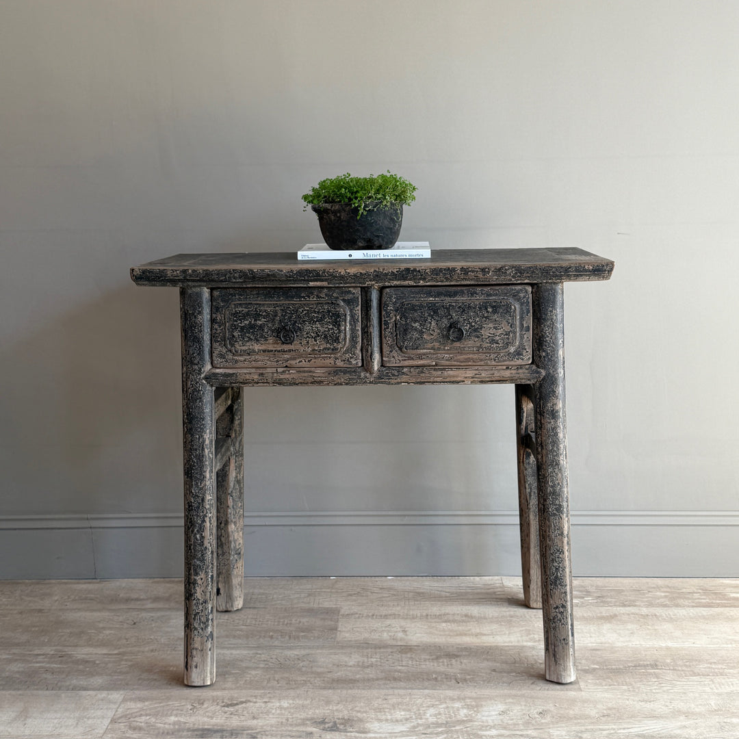Vintage-style wooden console table with two drawers against a plain wall.
