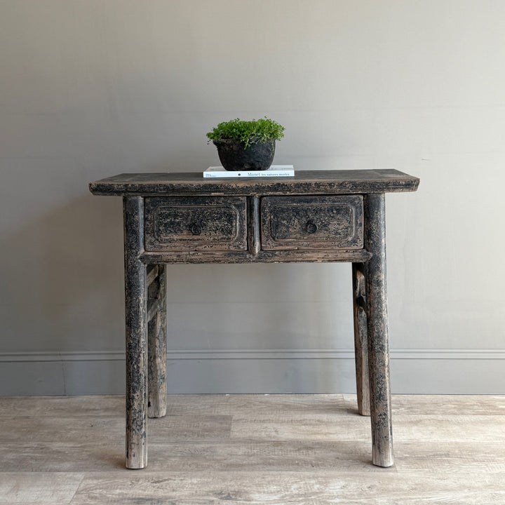 Vintage-style wooden console table with two drawers against a plain wall.