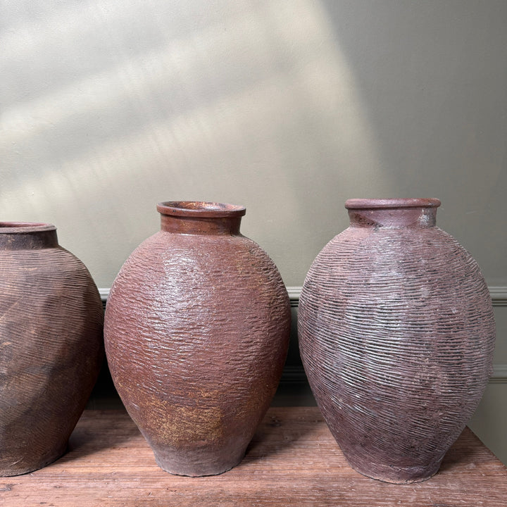 Antique Chinese stoneware storage jars displayed together, highlighting the natural variation in shape, colour and aged patina that makes every piece unique.
