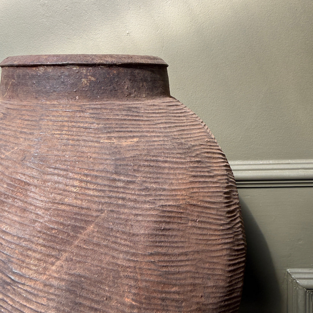 Side profile of a large antique Chinese stoneware storage jar, highlighting its sculptural form and hand-crafted proportions.
