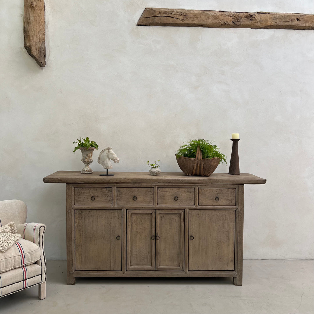 Wooden sideboard with decorative items against a textured wall.