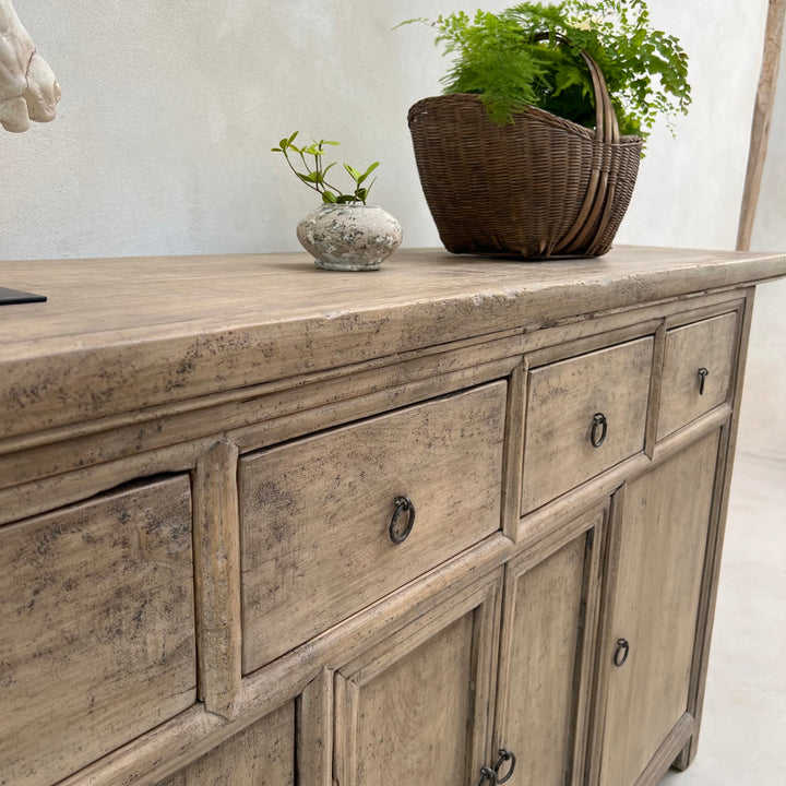 Wooden sideboard with drawers and a basket on top against a light background
