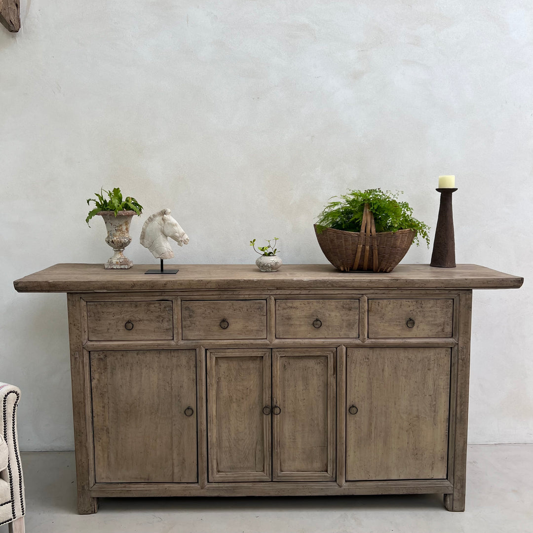 Wooden sideboard with decorative items against a plain wall
