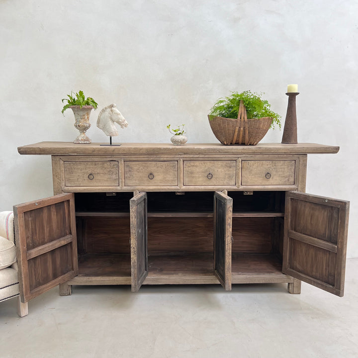Wooden sideboard with open doors against a white wall