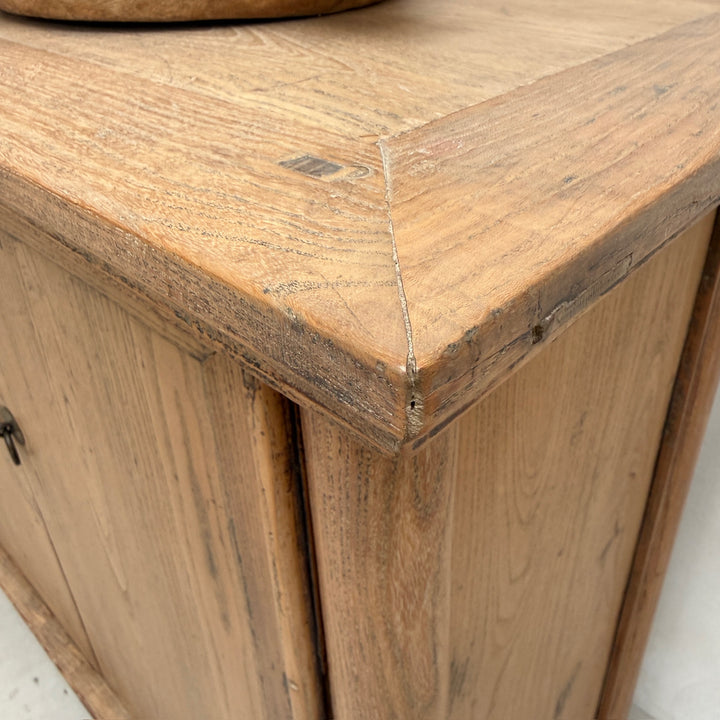 Close-up of a rustic wooden cabinet corner showing the natural wood grain, joint detail, and weathered finish.