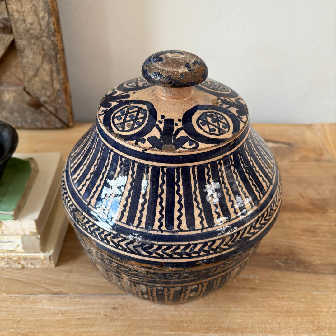 Ceramic jar with blue and beige patterns on a wooden surface