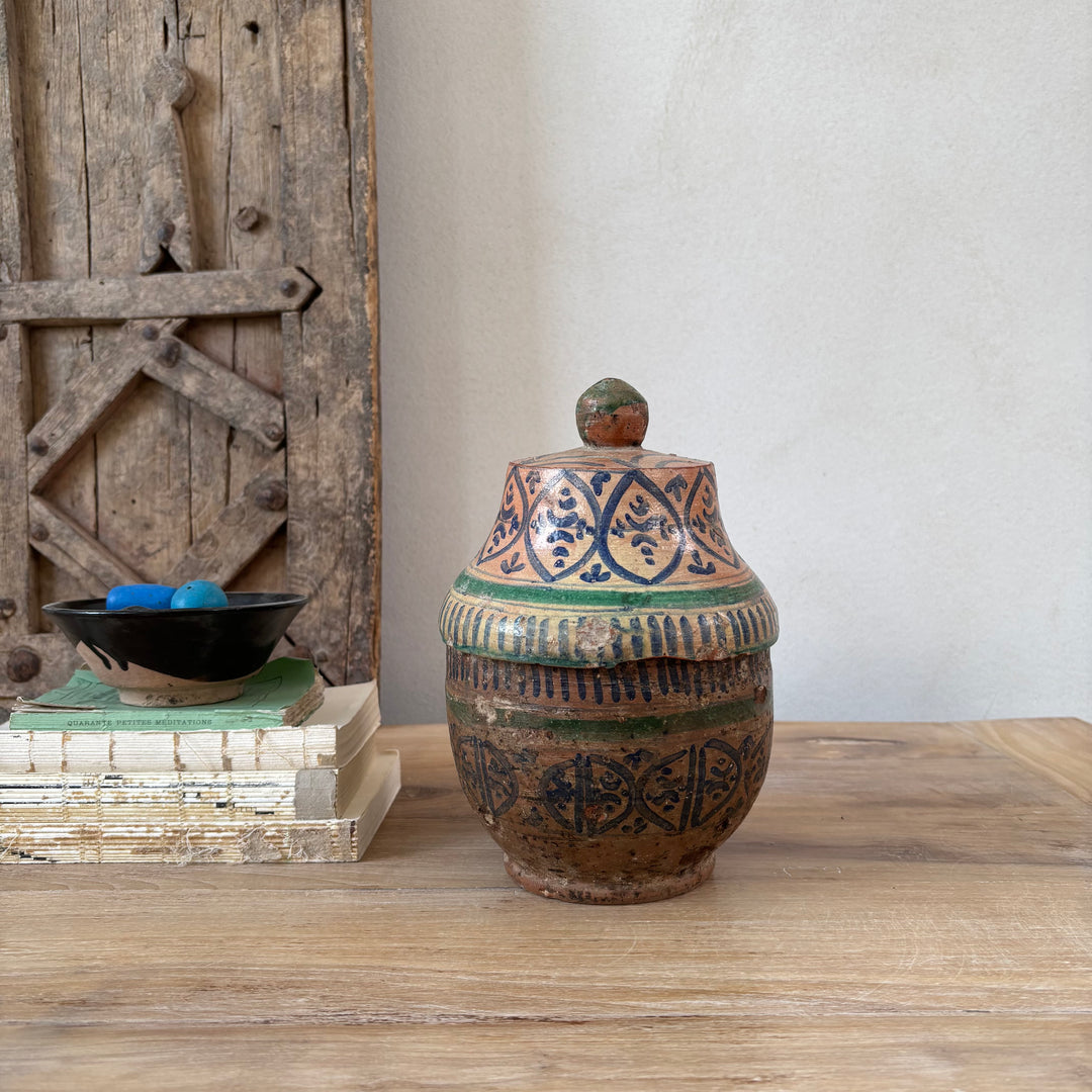 Decorative ceramic jar with intricate designs on a wooden surface.