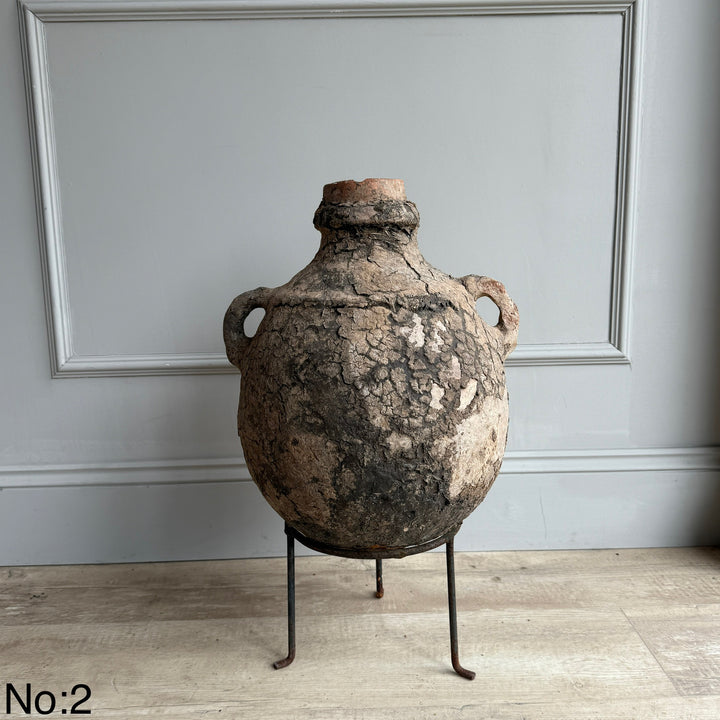 Vintage ceramic jar on a stand against a gray wall