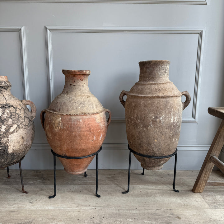 Three vintage-style vases on stands against a gray wall.
