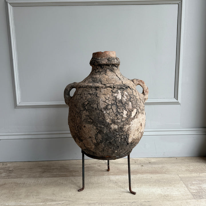 Vintage-style ceramic vase on a stand against a gray wall