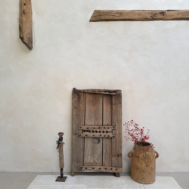 Vintage wooden door and rustic vase against a plain wall