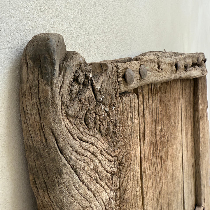 Close-up of a rustic wooden frame with detailed carvings on a light gray background