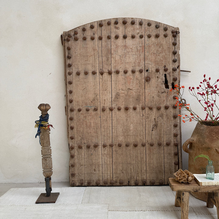 Large wooden door with metal studs in a room with decorative elements.