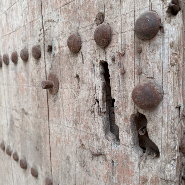 Close-up of an old wooden door with metal nails and a keyhole.
