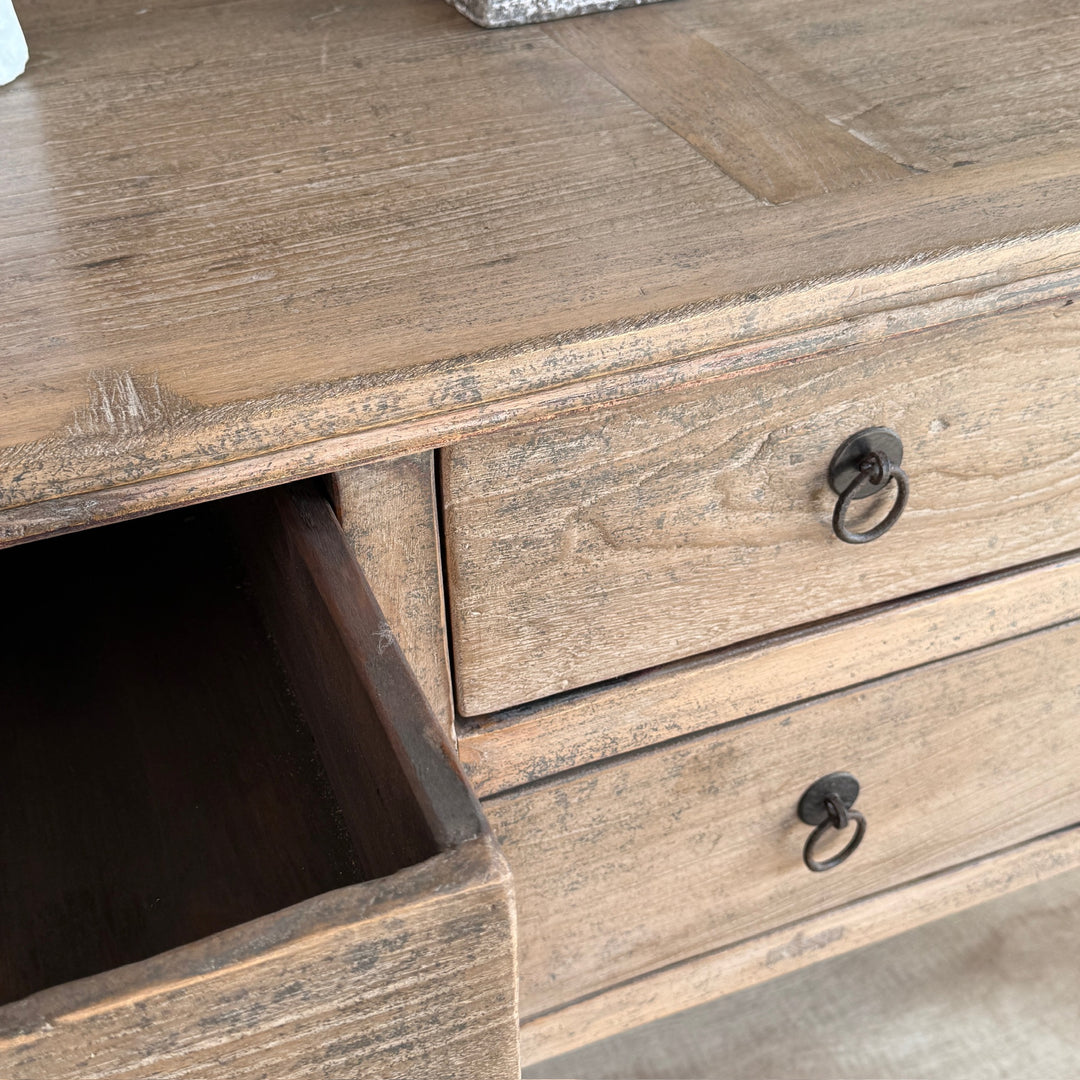 Wooden dresser with open drawer and two closed drawers, showing a rustic finish.
