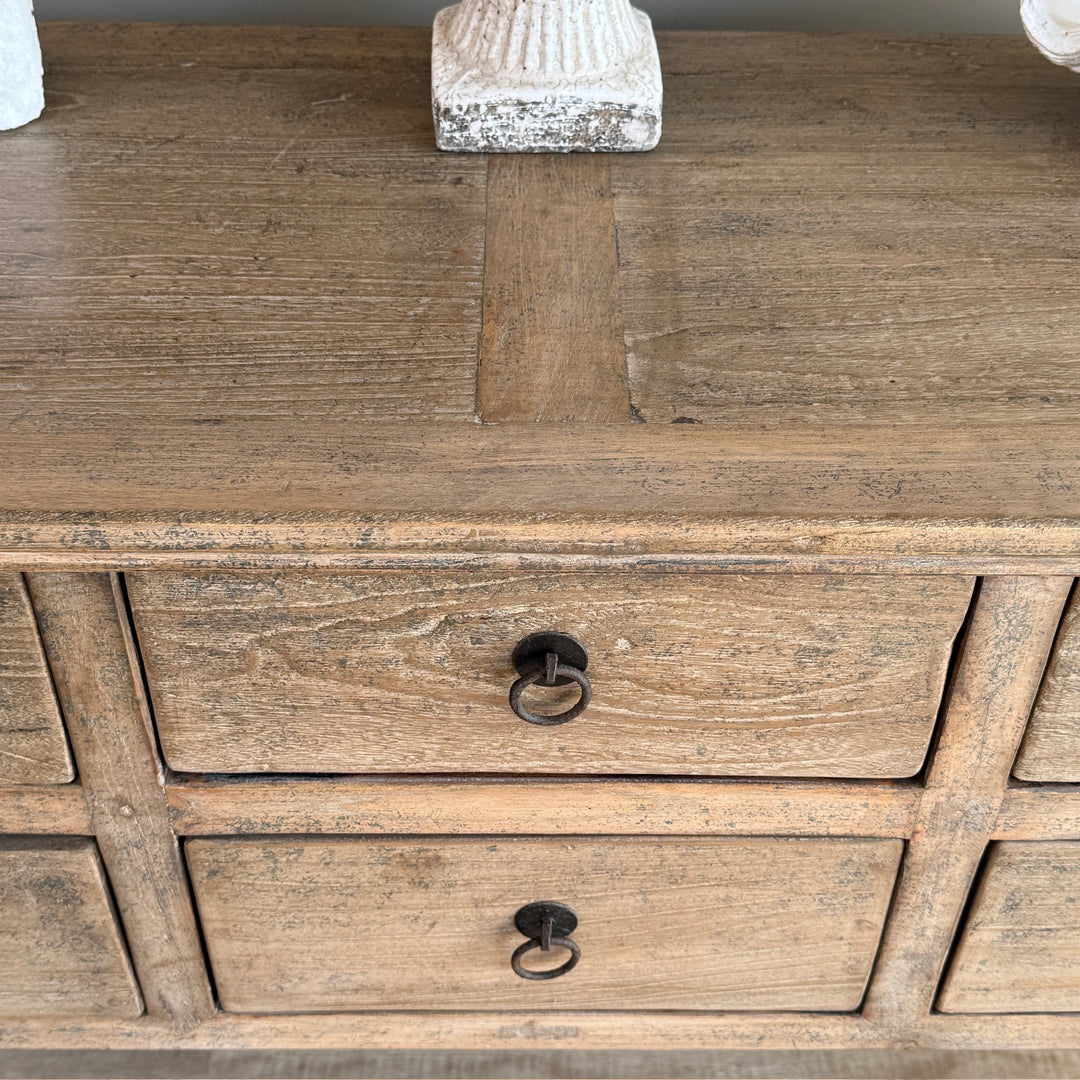 Wooden dresser with two drawers and metal handles on a wooden surface.