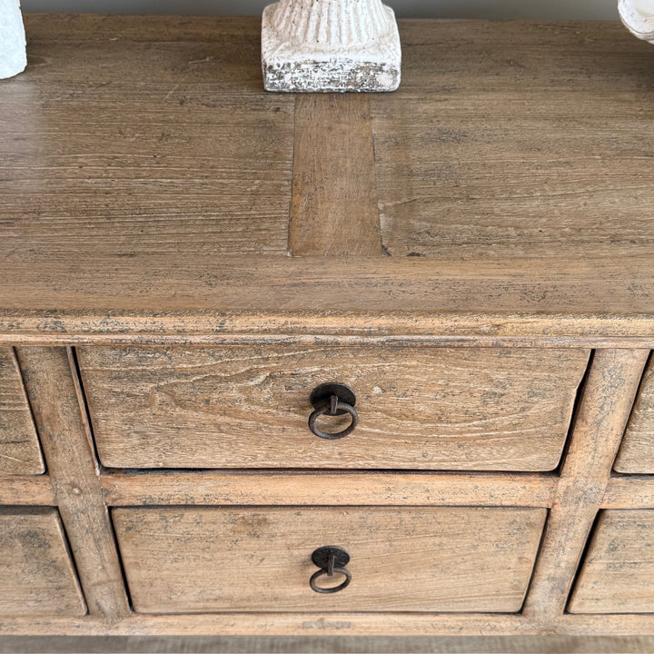 Wooden dresser with two drawers and metal handles on a wooden surface.