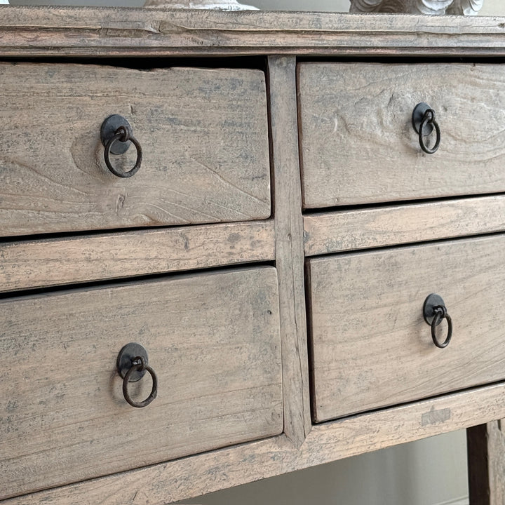 Wooden dresser with four drawers and metal ring handles.