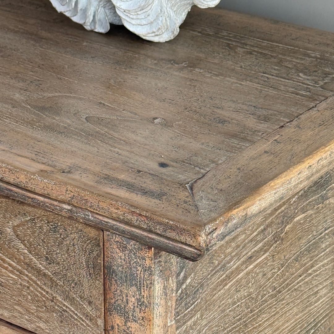 Close-up of a wooden surface with a rustic texture and a decorative shell on top.