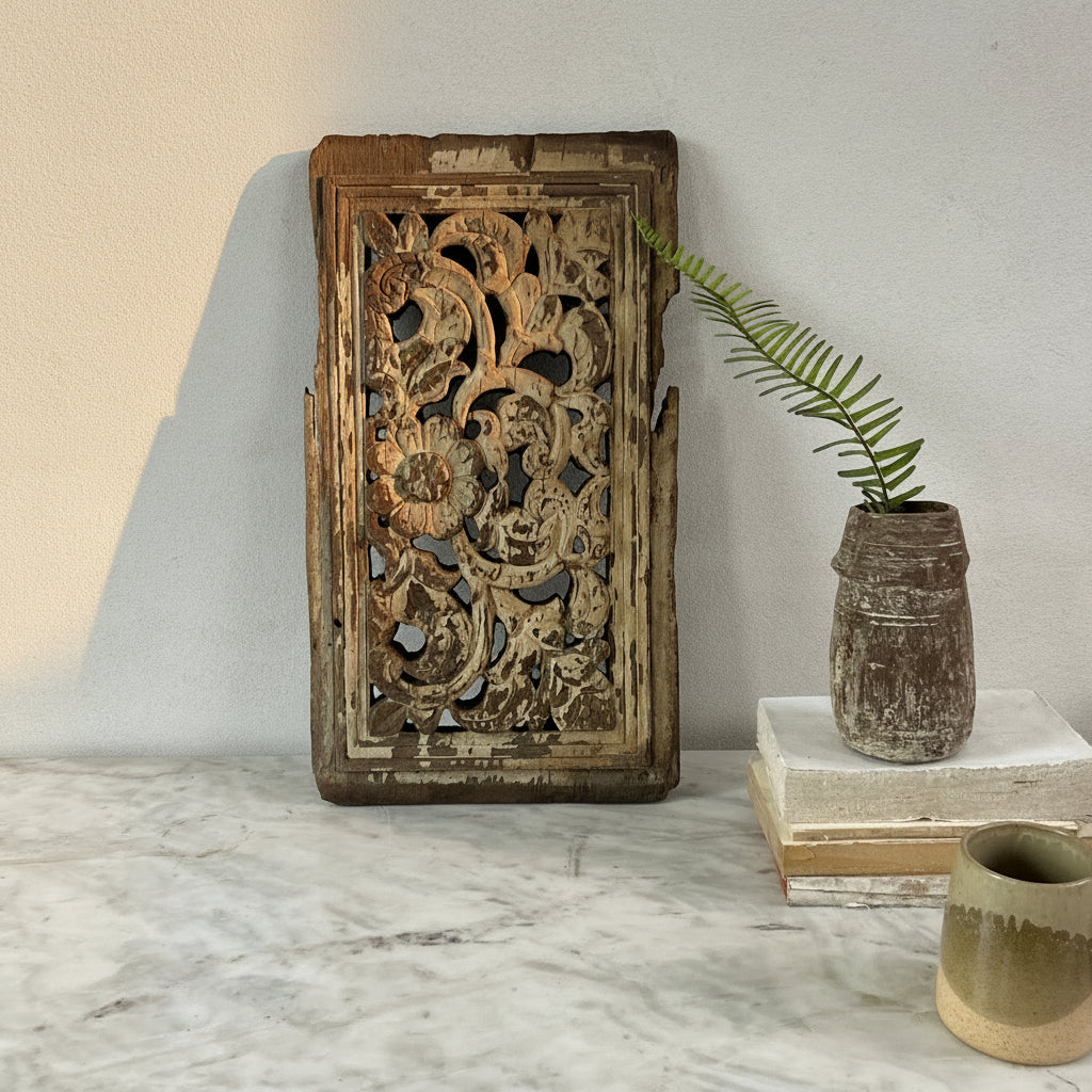 Decorative wooden panel with intricate carvings on a marble surface.