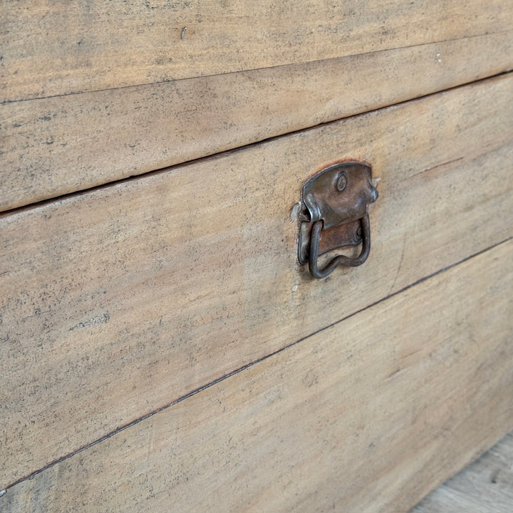 Close-up of a rustic wooden chest or trunk with a weathered metal latch on the front.