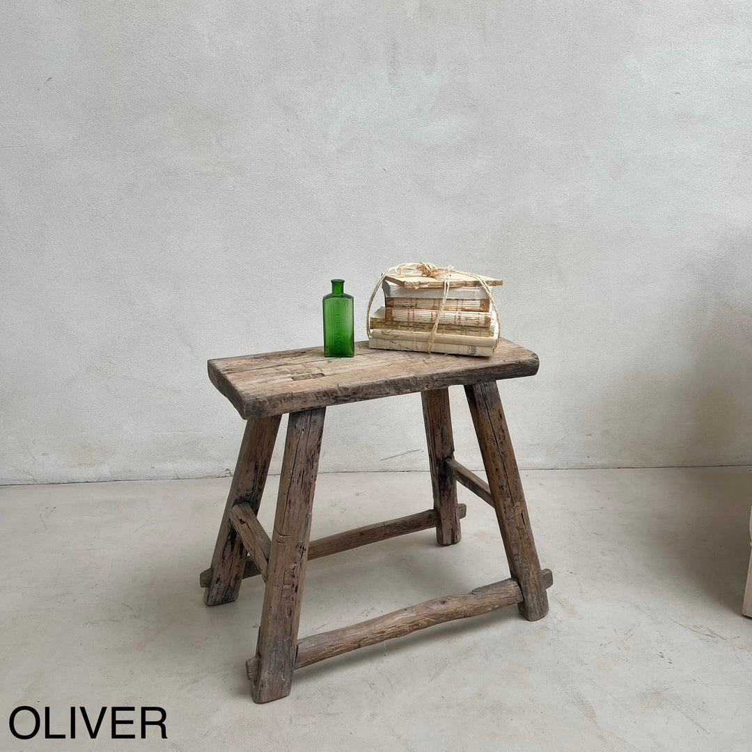 Wooden stool with a green bottle and woven basket on a plain background, branded &