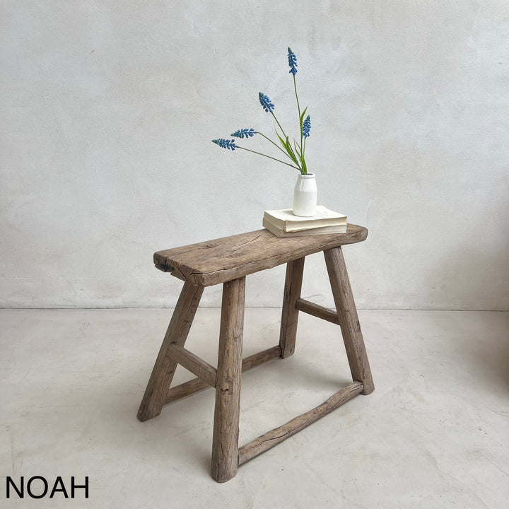 Wooden stool with a vase of blue flowers on a light gray background
