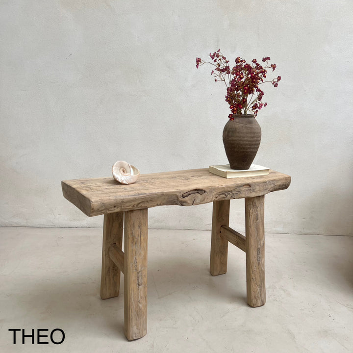 Wooden bench with a vase of dried flowers on a plain background