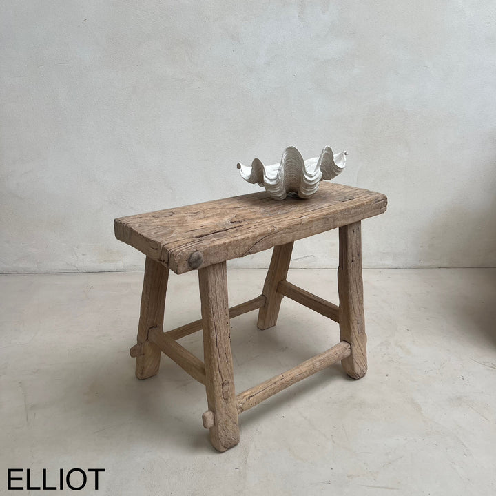 Wooden bench with a decorative shell on a plain background, featuring the brand &