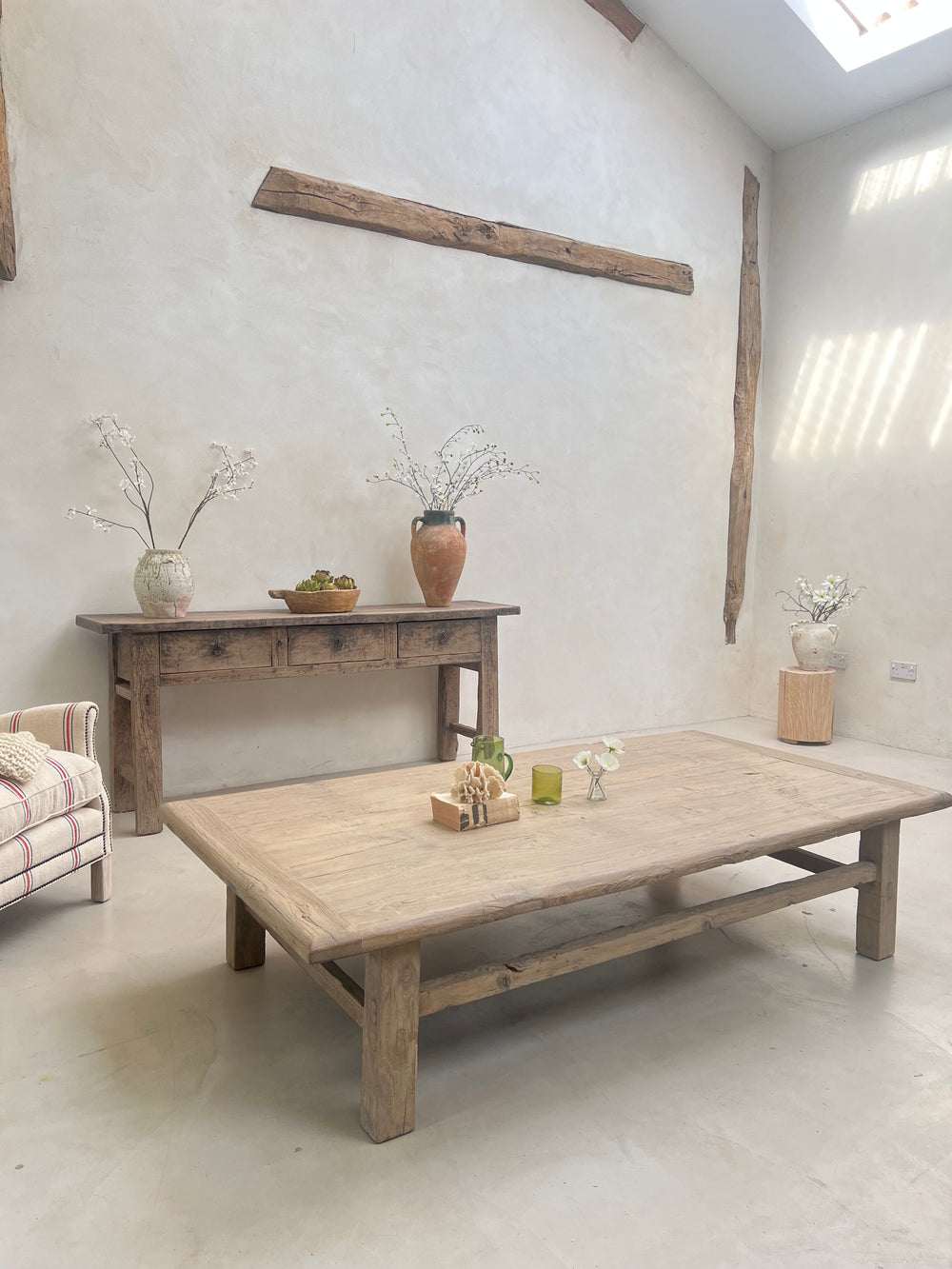 Wooden table and chairs in a minimalistic room with white walls and floor.