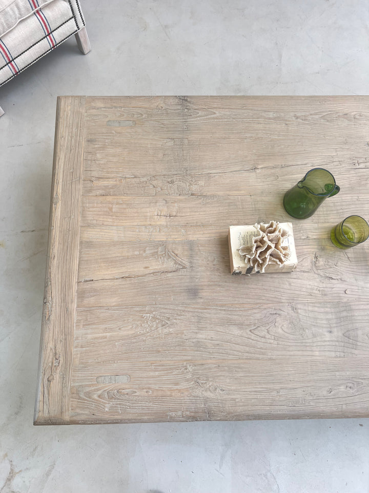 Wooden coffee table with decorative items on a light gray floor