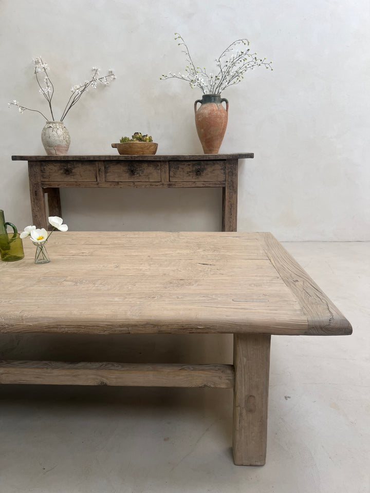 Wooden table with a rustic design against a plain wall.